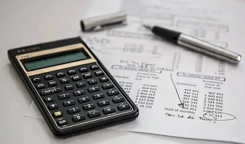 Calculator, pen, and financial spreadsheets representing private university tuition fees